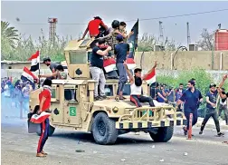  ??  ?? Protesters ride an Iraqi Army armoured vehicle during a demonstrat­ion in Iraq, on Friday