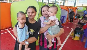  ?? — bernama ?? Safe and sound: Ida Mariana (left) and noraidah holding their children at the temporary relief centre at SMK bandau.