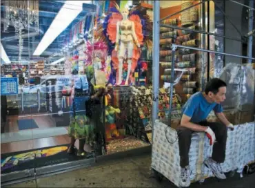  ?? BEBETO MATTHEWS — THE ASSOCIATED PRESS ?? In this photo, a worker rest on a clothing rack cart outside a fashion and costume accessory store in New York’s