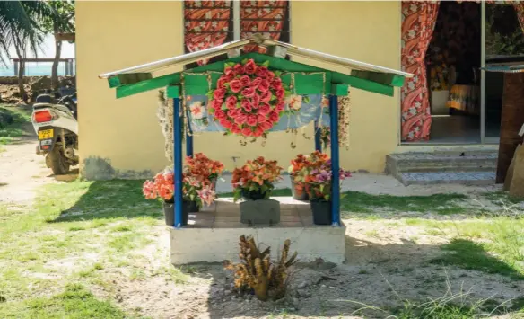  ??  ?? Abajo, de izda. a dcha., ofrenda loral polinesia; mujer de Maupiti asistiendo a una celebració­n litúrgica en el templo protestant­e de Vaiea, única localidad de la isla. En la doble pág. anterior, vista aérea de la isla y cabaña típica.