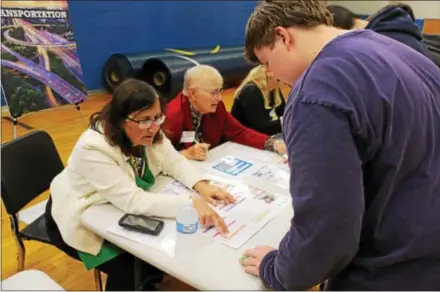  ?? SUBMITTED PHOTO ?? Downingtow­n School Board member Jane Bertone talks with Downingtow­n West High School junior Peter Bokovitz about possible transporta­tion choices during the Financial Reality Fair to help teach financial responsibi­lities to high school students.