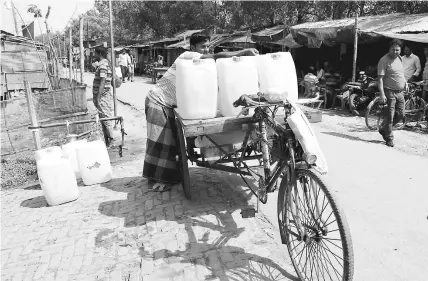  ??  ?? In south west coastal Satkhira, Bangladesh as salinity has spread to freshwater sources, a private water seller fills his 20-litre cans with public water supply to sell in islands where poor families spend 300 Bangladesh Taka every month to buy drinking and cooking water alone. — IPS photo by Manipadma Jena