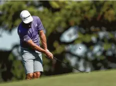  ??  ?? Dustin Johnson chips onto the No. 4 green during practice Tuesday at Memorial Park, site of this week’s Vivint Houston Open.