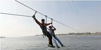  ?? — Reuters ?? A worker helps a man after he got stuck on a zip-line over the Sabarmati river on a winter afternoon in Ahmedabad.