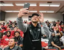  ?? Robin Jerstad/contributo­r ?? UIW head coach G.J. Kinne takes a selfie with his team during the team’s selection show watch party late Sunday morning.