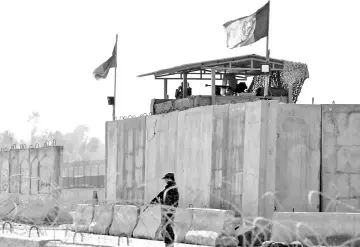  ??  ?? Afghan security forces stand guard near the site of an attack in Jalalabad, Afghanista­n. — Reuters photo