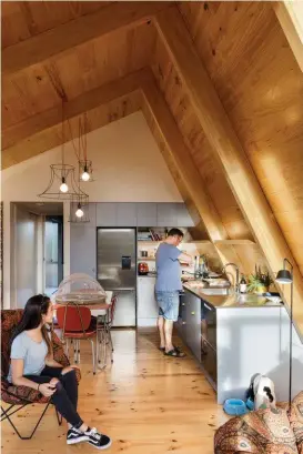  ??  ?? Below The primary structures were predominan­tly prefabrica­ted using 170mm-thick, insulated cross-laminated timber and glulam, with only the barest amount of painted MDF lining. Grace and Cymon in the kitchen and living area.