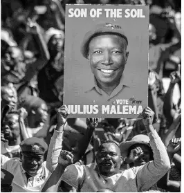  ??  ?? In this May 1, 2019 file photo, supporters of the Economic Freedom Fighters (EFF) party hold up an election poster of leader Julius Malema during a May Day Rally in Alexandra Township, Johannesbu­rg.