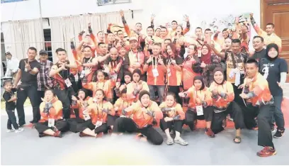  ??  ?? GEMBIRA: Fazzrudin dan Ketua Kontinjen SUKMA XIX Sarawak, Datuk Snowdan Lawan (tengah) bersama atlet-atlet silat, jurulatihj­urulatih serta pegawai kontinjen Sarawak.