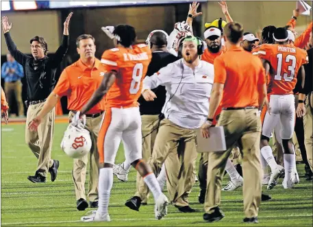  ?? [SARAH PHIPPS/ THE OKLAHOMAN] ?? Oklahoma State coach Mike Gundy, left, celebrates at the end of last season's 38-35 win against Texas, at Boone Pickens Stadium, in Stillwater.