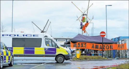  ?? Joe Giddens The Associated Press ?? Activists from Extinction Rebellion block the entrance to the Amazon fulfilment centre preventing lorries from entering or leaving on Black Friday, the global retail giant’s busiest day of the year, in Coventry, England.