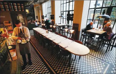  ?? ?? A server at the “Der Elefant” restaurant prepares drinks and food on a tray Tuesday in Warsaw. Der Elefant was the first, and until recently, the only restaurant in Poland to require proof of vaccinatio­n to dine.