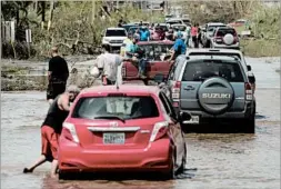  ?? CARLOS GIUSTI/AP ?? Residents drive on a flooded road Friday in Toa Baja, Puerto Rico.