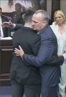  ?? Mark Wallheiser/Associated Press ?? Florida’s House Speaker Richard Corcoran, center, hugs Hunter Pollack, a brother of high school shooting victim Meadow Pollack, after the school safety bill passed the House 67-50 on Wednesday at the state Capital in Tallahasse­e.