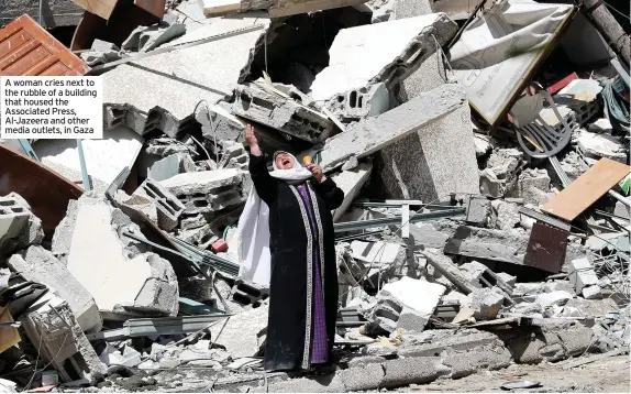  ??  ?? A woman cries next to the rubble of a building that housed the Associated Press, Al-Jazeera and other media outlets, in Gaza