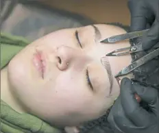  ?? Rebecca Droke/Post-Gazette ?? Hillary Evans maps and measures the eyebrows of Alexis Weyandt, 20, before microbladi­ng them at Scratch Studio in Dormont.