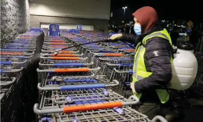  ?? Photograph: Anadolu Agency/Getty Images ?? A worker sanitizes shopping carts as people line up in the early morning at Walmart on Black Friday.