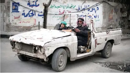  ??  ?? DOUMA: A Syrian man and his son drive in vehicle battered by years on conflict in the rebel-held area of Douma, east of the capital Damascus yesterday. — AFP