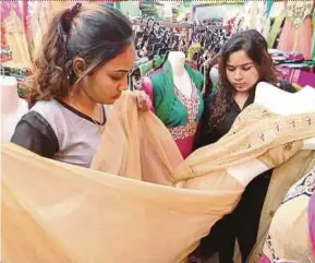  ?? PIC BY SHARUL HAFIZ ZAM ?? S. Nurissini (left) and her worker arranging saris in her shop in Alor Star.