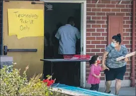  ?? Brian van der Brug Los Angeles Times ?? L.A. COUNTY is spending $14.9 million to help schools close the technology gap. Above, a parent picks up a laptop at Patrick Henry Middle School last month.