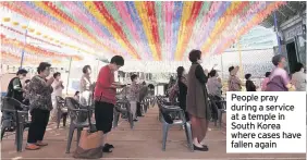  ??  ?? People pray during a service at a temple in South Korea where cases have fallen again