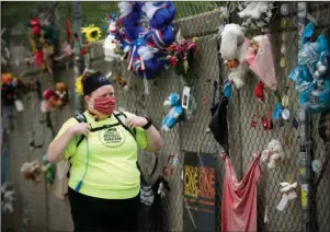  ?? The Associated Press ?? 168 MINUTES: Holley Mangham looks at the fence outside the Oklahoma City National Memorial and Museum before walking for 168 minutes to honor victims on the 25th anniversar­y of the bombing of the Alfred P. Murrah Federal Building on Sunday in Oklahoma City. Mangham had planned to run the half marathon in the Oklahoma City Memorial Marathon which would have taken place the next week and is now postponed. The memorial remains closed and did not hold a live remembranc­e ceremony due to coronaviru­s restrictio­ns.