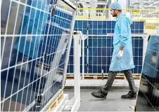  ?? ?? Employee walking past solar panels at an Adani Group factory.