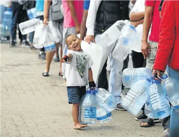  ?? Picture: Esa Alexander ?? Joshua Brits queues at Newlands Spring with his father, Ricardo, as Capetonian­s face Day Zero.