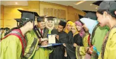  ??  ?? The KKLW Minister Award recipient, Faizi Abd Kadir (second from left) showing the award plaque to friends after the convocatio­n ceremony.