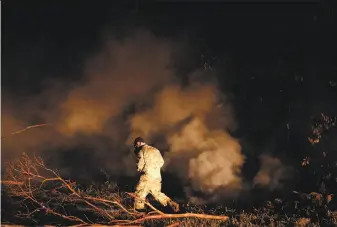  ?? Jae C. Hong / Associated Press ?? Sgt. Carl Satterwait­e of the National Guard tests air quality near cracks emitting volcanic gases from a lava flow in the Leilani Estates subdivisio­n near the town of Pahoa on Thursday.