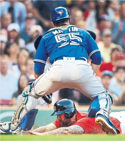  ?? ADAM GLANZMAN/GETTY IMAGES ?? Red Sox baserunner Sam Travis scores in a cloud of dust past Blue Jays catcher Russell Martin in a five-run Boston second inning on Friday night at Fenway Park in Boston. The Jays struck back with five of their own in the third and won 13-7.