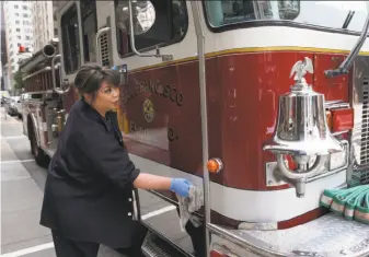 ?? Paul Chinn / The Chronicle ?? Firefighte­r Willa Ortega wipes down a fire engine at Station 13 on Sansome Street in S.F. Affordable-housing units would be built above the firehouse under a supervisor’s plan.