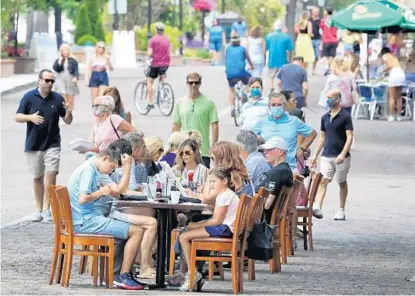  ?? JOE BURBANK/ORLANDO SENTINEL ?? Visitors to Park Avenue in Winter Park dine al fresco as restaurant­s and shops opened Mother’s Day weekend in the popular district with Phase One restrictio­ns in place in response to the coronaviru­s crisis. Current restrictio­ns for restaurant­s for most of Florida include socially distanced outdoor dining and 25% maximum capacity for indoor dining.