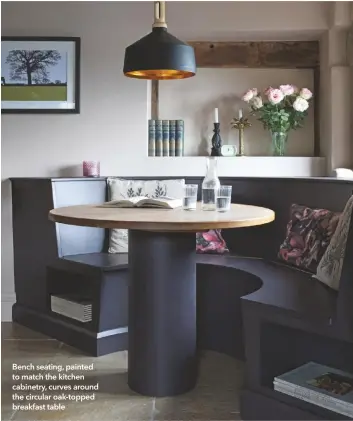  ??  ?? Bench seating, painted to match the kitchen cabinetry, curves around the circular oak-topped breakfast table
