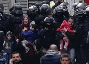  ?? STEVE PARSONS/PA WIRE/TNS ?? A family is escorted from the scene of the police raid.