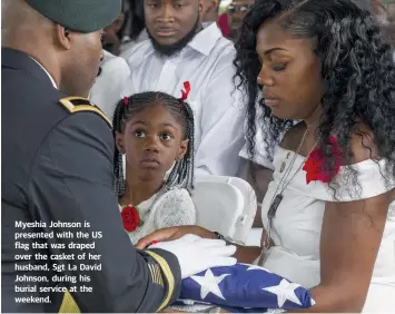  ??  ?? Myeshia Johnson is presented with the US flag that was draped over the casket of her husband, Sgt La David Johnson, during his burial service at the weekend.