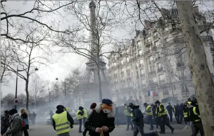  ?? AP PHOTO/KAMIL ZIHNIOGLU ?? Yellow vest protesters run away from tear gas fired by riot police as they keep pressure on French President Emmanuel Macron’s government, for the 13th straight weekend of demonstrat­ions, during a demonstrat­ion in Paris, France, on Saturday.