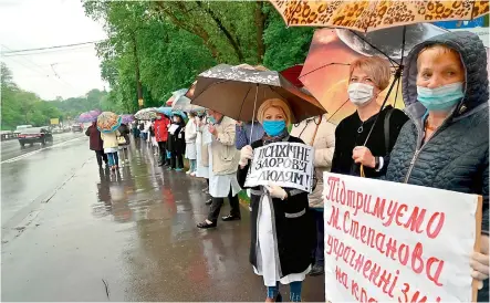  ?? — AFP ?? Doctors and nurses wearing masks hold placards as they stand along a thoroughfa­re during their protest against cuts to psychiatri­c care funding in the Ukrainian capital of Kiev on Tuesday.