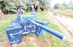  ??  ?? OMAR (kanan) bersama anaknya Fauzi (kiri) membetulka­n bendera parti Barisan Nasional pada replika kereta kebal yang dibina di lorong Hassan Ya’acob, Sungai Balang Laut, di sini. Beliau dan anaknya mengambil masa kira-kira seminggu untuk menyiapkan...