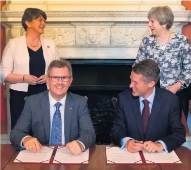  ??  ?? Prime Minister Theresa May stands with DUP leader Arlene Foster as DUP MP Sir Jeffrey Donaldson signs the paperwork in June 2017 with the then Parliament­ary Secretary to the Treasury, Gavin Williamson, to cement the party’s confidence and supply deal to support Mrs May’s minority Conservati­ve government in Commons votes