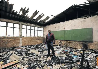  ?? Picture: WERNER HILLS ?? GRIM OUTLOOK: Vandalism is a problem at the James Jolobe Senior Secondary School in Motherwell. There is no fence and vandals have broken most of the windows and set classrooms alight. Principal Fundile Diamond looks at the damage done to classrooms about six months ago