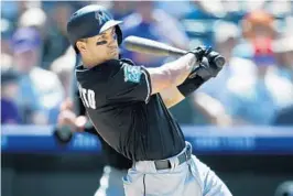  ?? DAVID ZALUBOWSKI/AP ?? Marlins catcher J.T. Realmuto hits a grand slam in the seventh inning of Saturday’s game against the Rockies in Colorado.