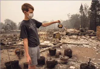 ?? Paula Bronstein / Associated Press ?? Jacen Sullivan, 14, from Talent, Ore., holds a burned tomato he found in the garden at his burned home as destructiv­e wildfires devastate the region.