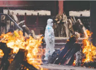  ?? ANINDITO MUKHERJEE/GETTY IMAGES ?? A man in protective gear delivers last rites to a relative who died of COVID at a New Delhi crematoriu­m. With over 200,000 new cases a day, concern is growing in India over a new variant.