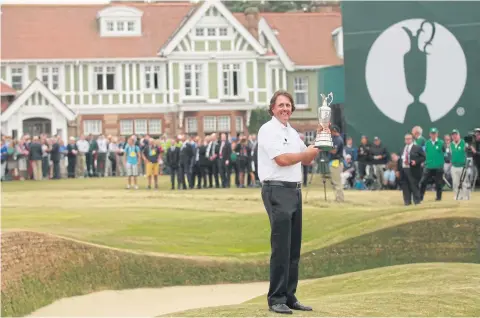  ?? AP ?? Phil Mickelson holds up the Claret Jug trophy in front of the clubhouse after winning the 2013 British Open at Muirfield.