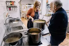  ??  ?? LAGARBETE. Anna Starrbrink är del i veckans matlag och får hjälp av Erik att bära grytan till serveringe­n av kvällens middag.