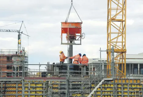  ??  ?? Constructi­on workers work at a large residentia­l constructi­on site in Munich, southern Germany, Feb. 17, 2021.