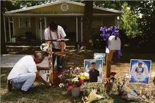  ?? Jae C. Hong / Associated Press ?? Jose Mata, top, a brother of Xavier Lopez, and a man, who declined to give his name, place a wooden cross decorated with a baseball bat at a memorial honoring his brother outside his home in Uvalde, Texas, on Tuesday. Lopez was one of the students killed in last week's shooting at Robb Elementary School.