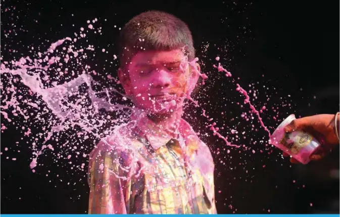  ??  ?? An Indian boy gestures as another throws coloured water during Holi festival celebratio­ns in Chennai on March 2, 2018. Holi, the popular Hindu spring festival of colors, is observed in India at the end of the winter season on the last full moon of the...