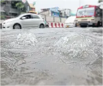  ??  ?? Water spurts from a flooded drainage system near Kasetsart University intersecti­on yesterday.